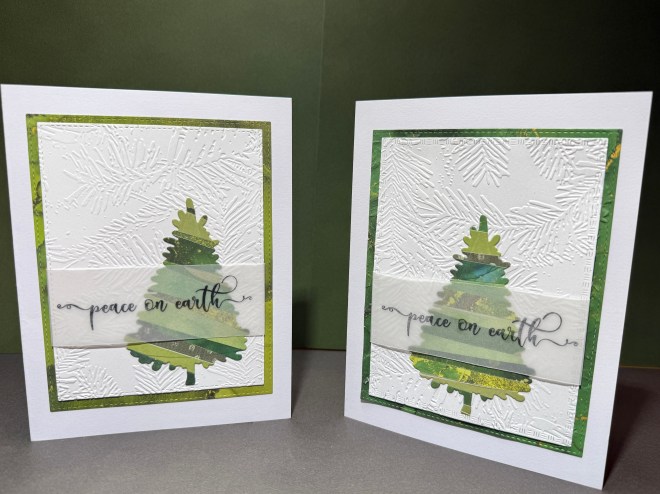 Two handmade Christmas cards featuring embossed white backgrounds with green accents. Each card displays a distinct paper Christmas tree and a vellum overlay with the phrase 'peace on earth'.