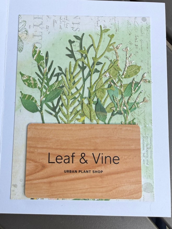 A decorative card displaying greenery patterns and the text 'Leaf & Vine Urban Plant Shop' on a wooden background.