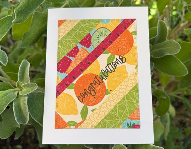 A colorful 'Congratulations' greeting card featuring vibrant fruit illustrations, including oranges, lemons, and strawberries, set against a geometric patterned background.